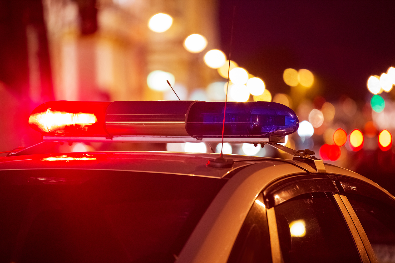 Red light flasher atop of a police car. City lights on the background.