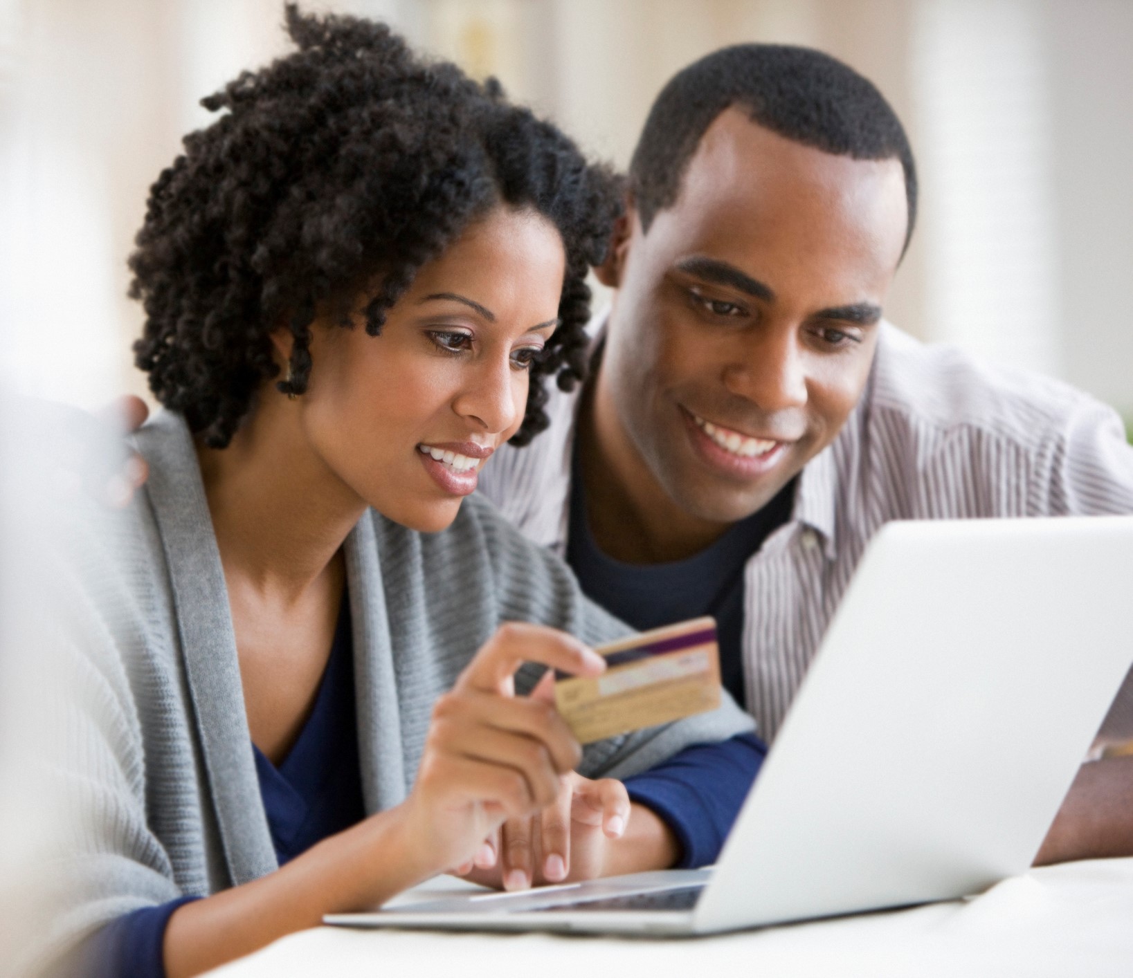 Couple holding credit card and using laptop