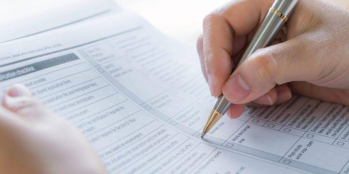 Hand with pen over application form