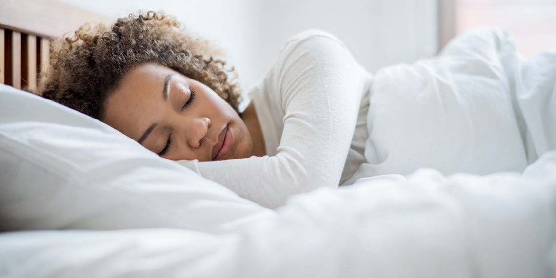 Tired black woman sleeping and looking very comfortable in her bed