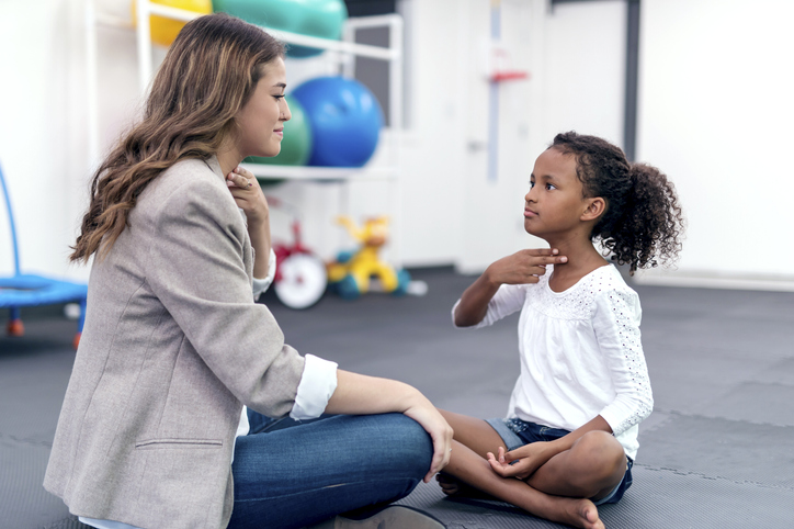 Adult female therapist guiding a young girl in therapy exercises
