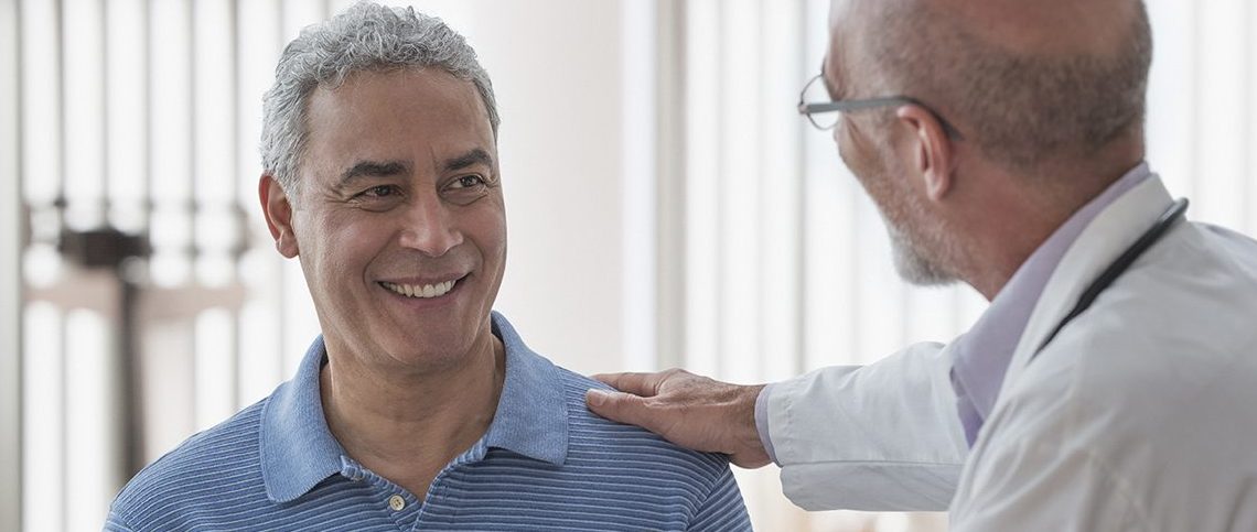 Doctor using digital tablet and talking to patient in office