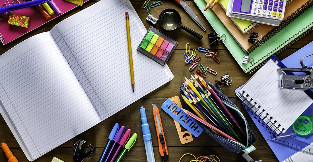 Back to school themes. Overhead shot of stationery on wood desk with paper notepad and frame of school office supplies