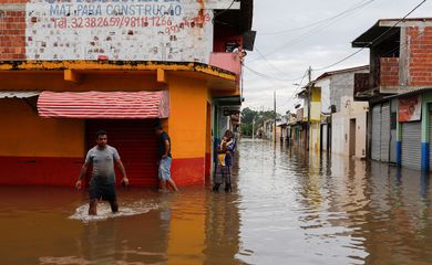 People walk through water along a street during floods caused by heavy rain in Itajuipe, Bahia state, Brazil December 27, 2021. REUTERS/Amanda Perobelli