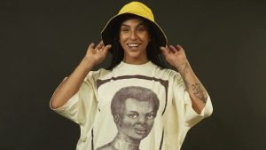 Linn da Quebrada chega ao BBB 22 com camiseta”Monumento à voz de Anastácia”