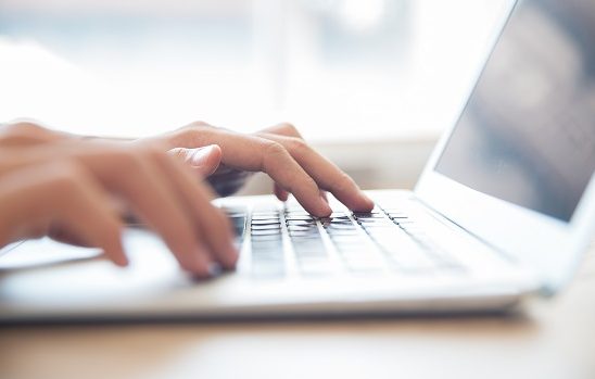 Close-up of male hands typing on laptop keyboard indoors. Businessman working in office or student browsing information