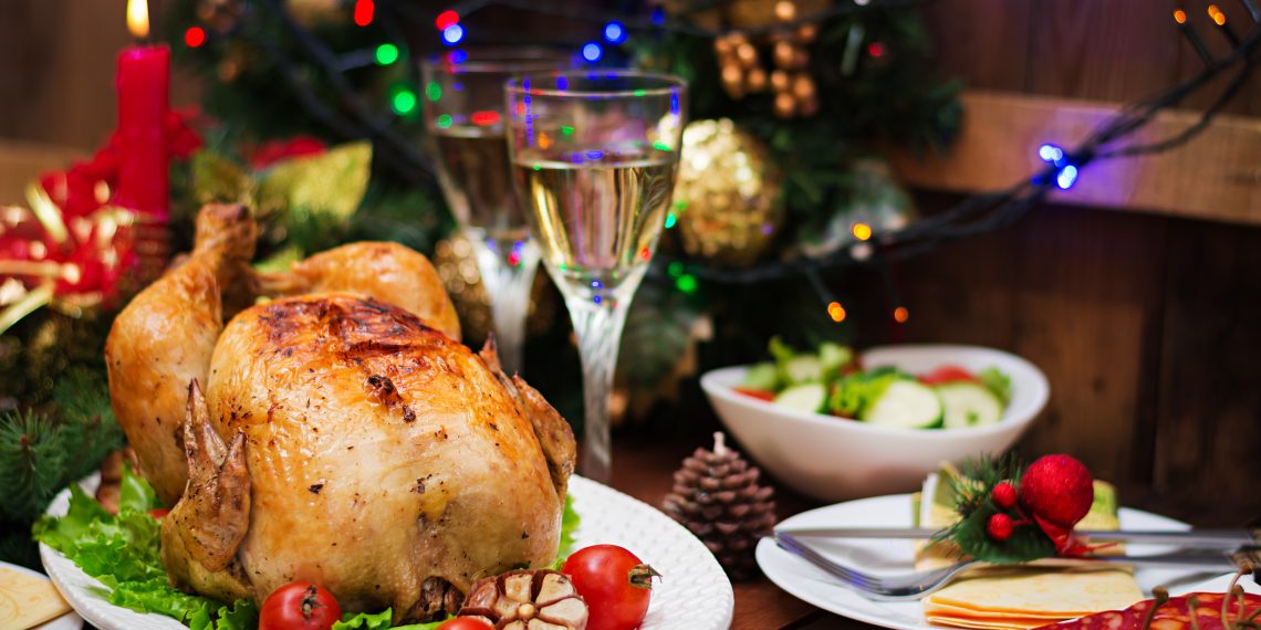 Baked turkey or chicken. The Christmas table is served with a turkey, decorated with bright tinsel and candles. Fried chicken, table. Christmas dinner.