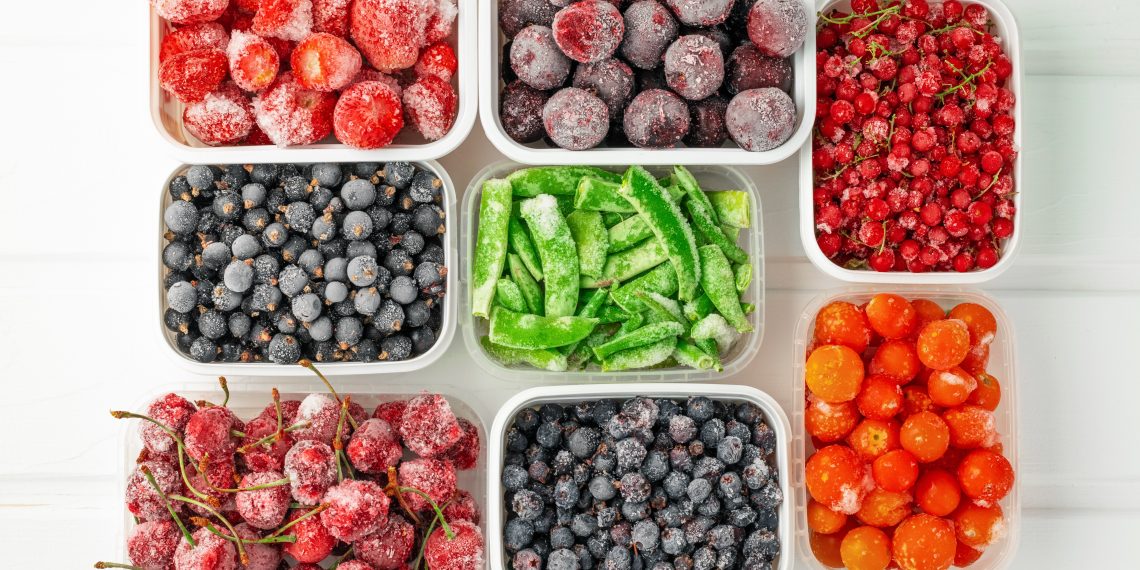 Top view frozen vegetables and berries in plastic containers.