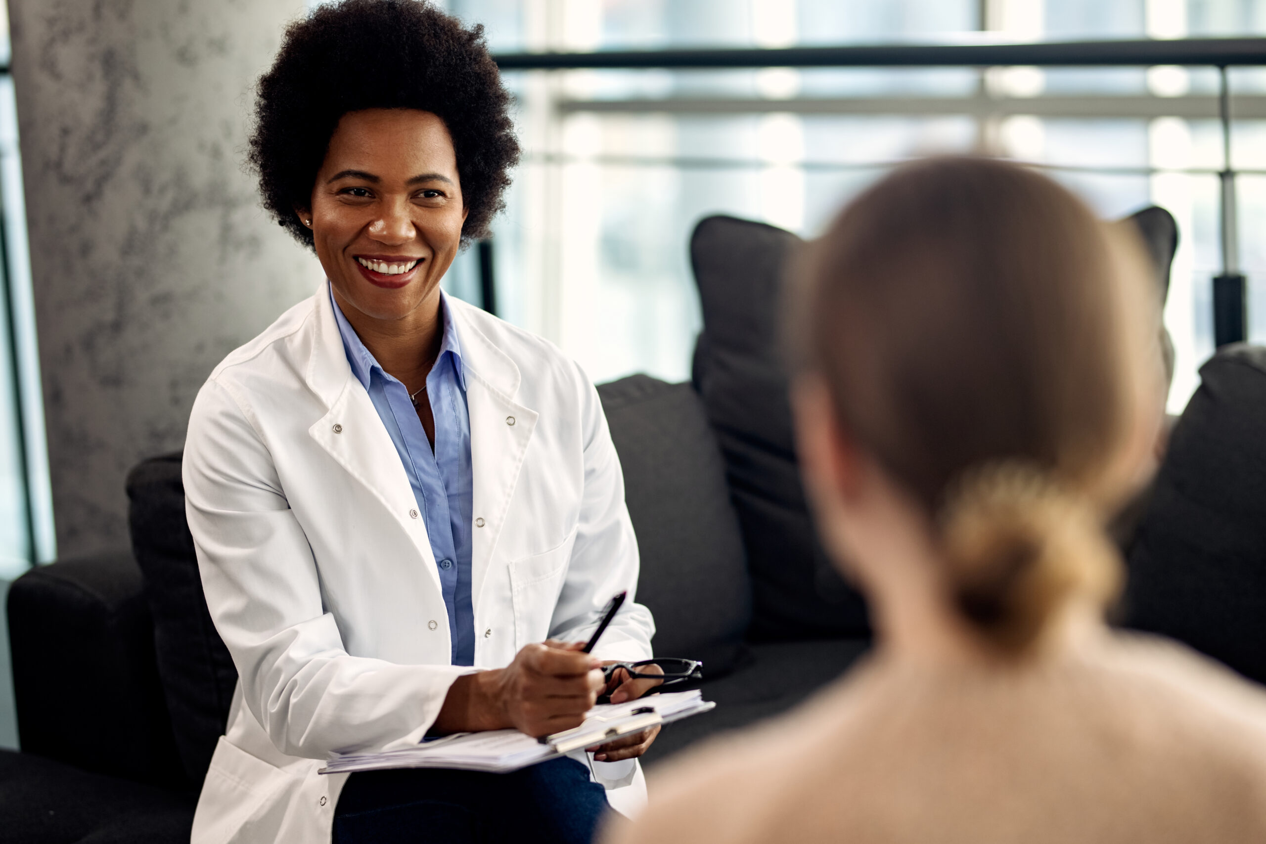 Happy black counselor communicating with a patient during a psychotherapy appointment at her office.