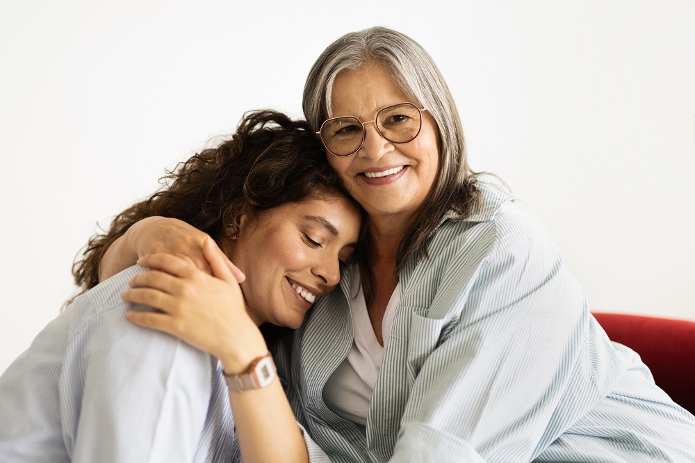 Happy european elderly woman hugging millennial lady, enjoy free time, isolated on white studio background. Family support, female generation, mother daughter, relationship at weekend