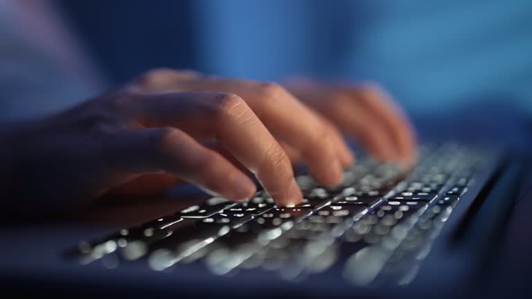 Close up of Hands typing on laptop keyboard on blue blurred background