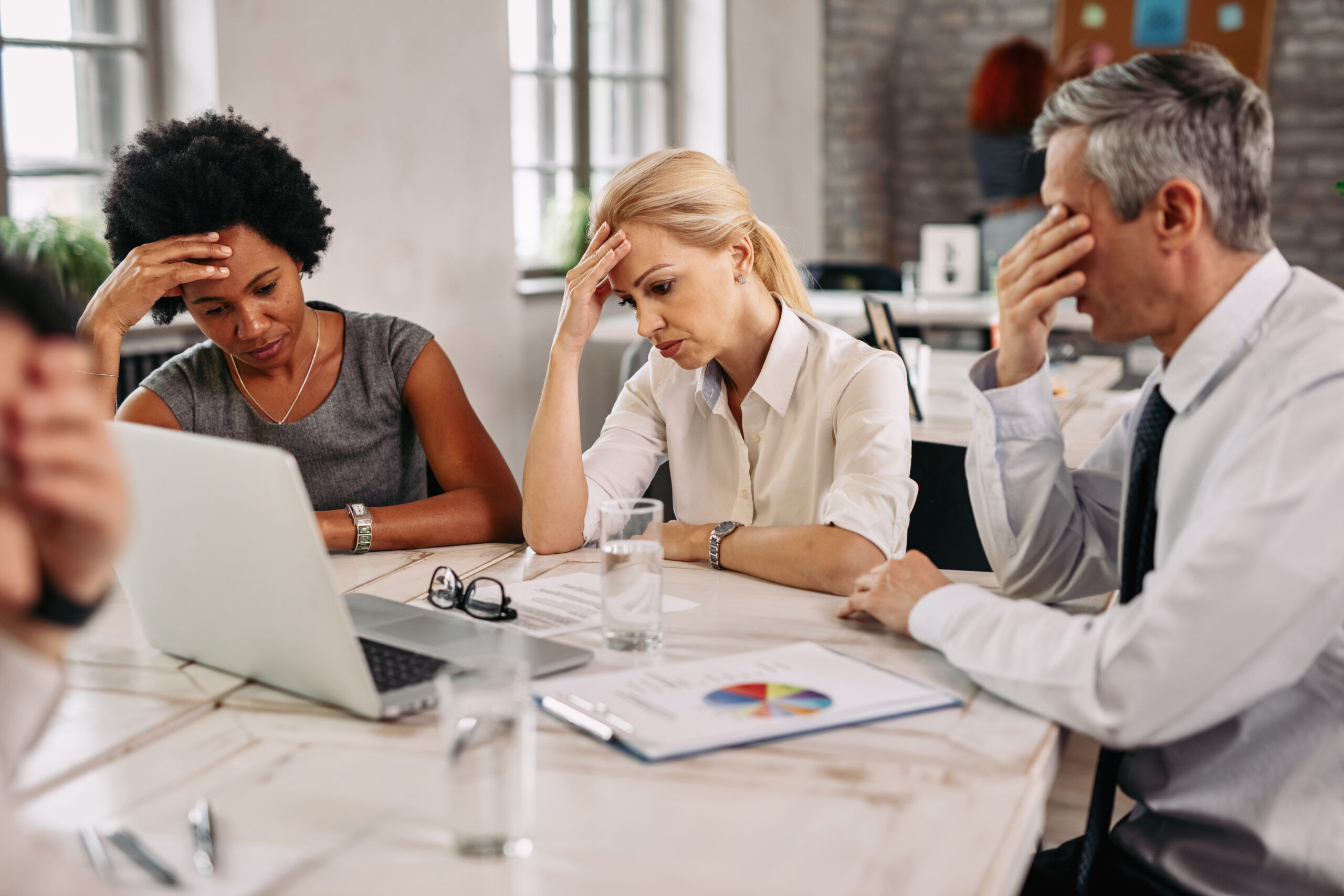 Group of business colleagues having a headache while working on laptop and trying to solve the problems during a meeting.